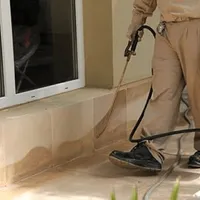 General pest control technician spraying exterior perimeter around a home in Knoxville, TN