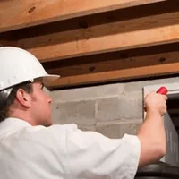 Termite inspection technician checking a basement wall and framing for termite activity in Knoxville, TN