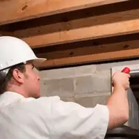 Termite inspection technician checking a basement wall and framing for termite activity in Knoxville, TN
